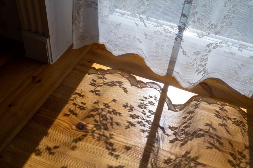 Sunlight through a lace curtain falling across old floorboards in a Westmount house in Edmonton.