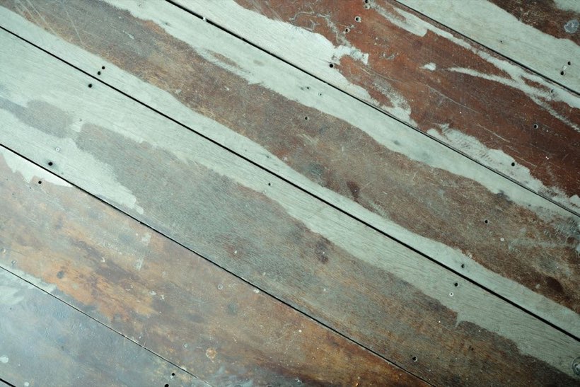 Damaged and patched oak floorboards in an Edmonton house waiting for board repair.